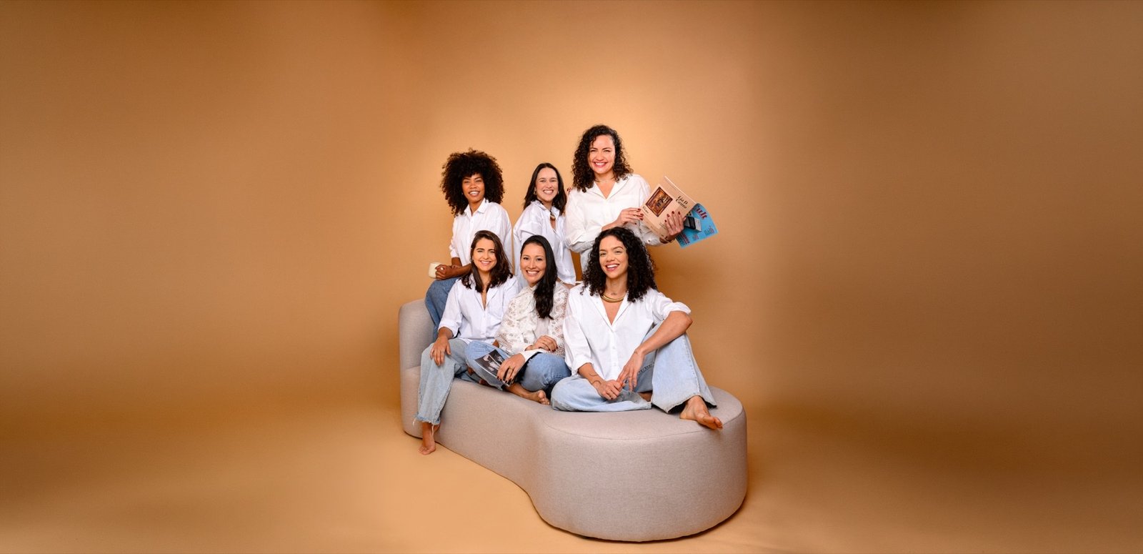 Equipe do Instituto Maat reunida em estúdio, seis mulheres sorrindo em um sofá bege
